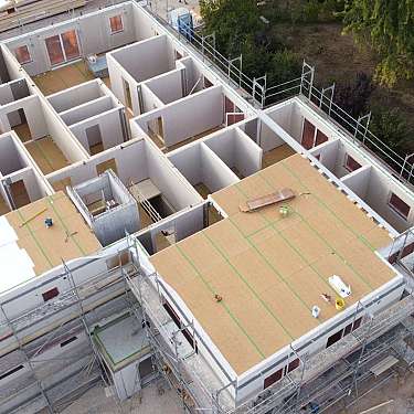 Luftaufnahme eines Hauses im Bau mit Gerüst und mehreren Innenwänden.
